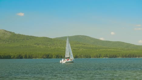 sailboat on a serene lake, surrounded by mountains and forest