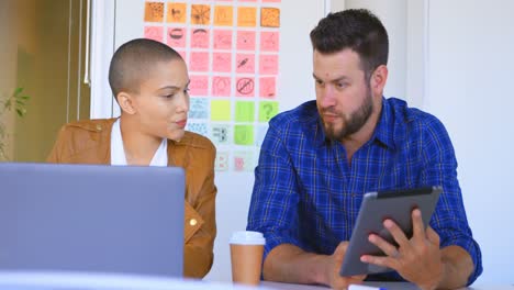 Front-view-of-young-caucasian-business-colleagues-discussing-over-digital-tablet-in-office-4k