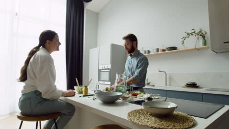 fröhliches paar, das in einer modernen küche plaudert und einen leckeren salat zubereitet 1