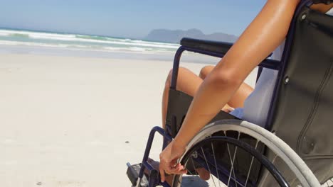 mujer discapacitada sentada en silla de ruedas en la playa 4k