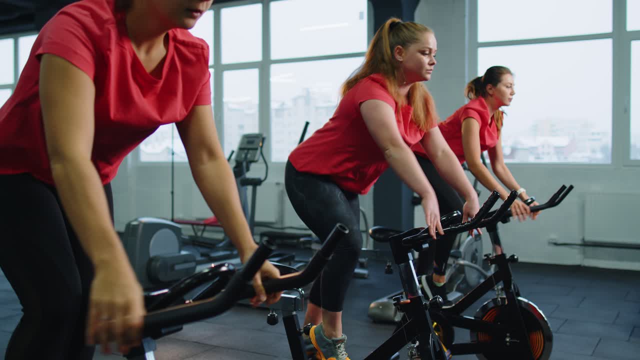 체육관 에서 자전거 를 타고 에어로빅 라이딩 훈련 을 하는 단체 운동 여자 들