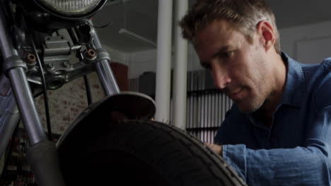 front view of caucasian male mechanic repairing motorbike in repair garage 4k