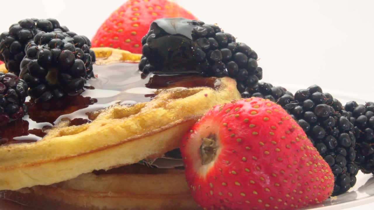 A vibrant breakfast scene featuring fresh strawberries and blackberries paired with warm golden waffles