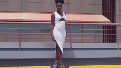 on a city rooftop, a black girl in a white dress stands overlooking the skyline