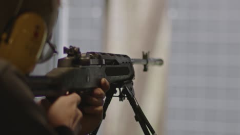 shooter aiming and firing a ruger mini-14 rifle at a shooting range in slow motion