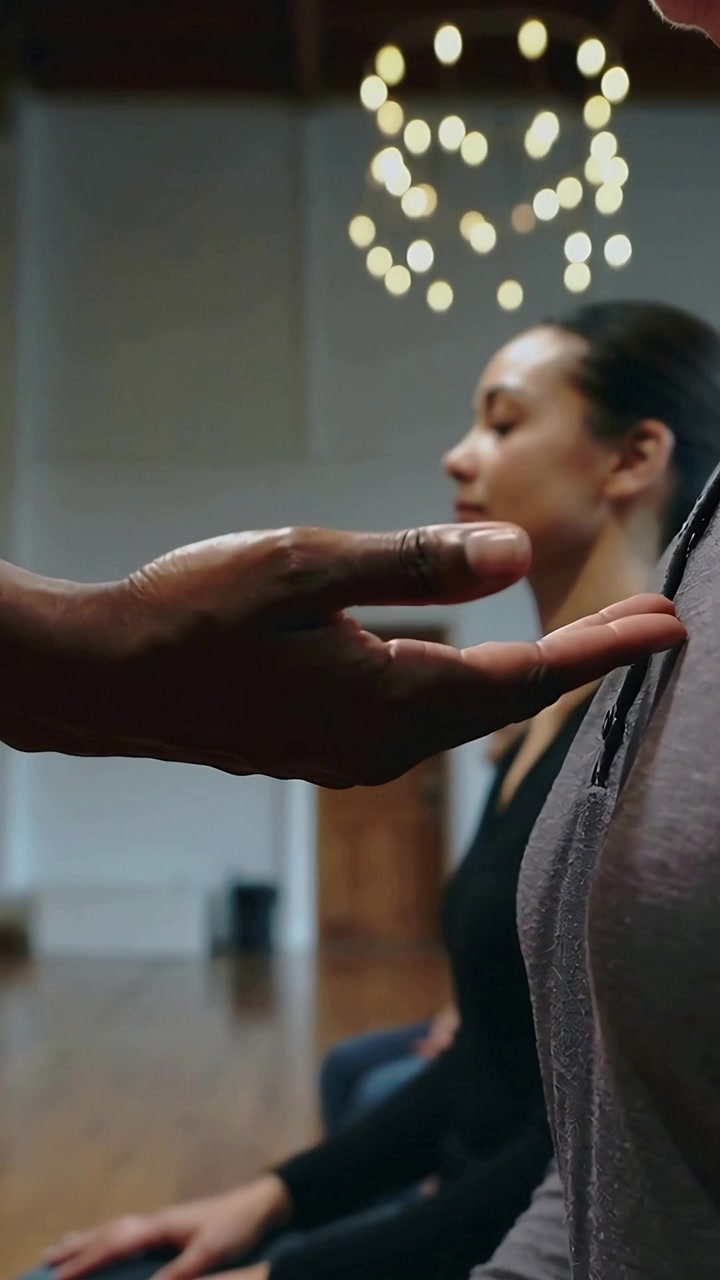 Vertical video: Extending guide open palm hovering near seated woman in dark top for calm in studio