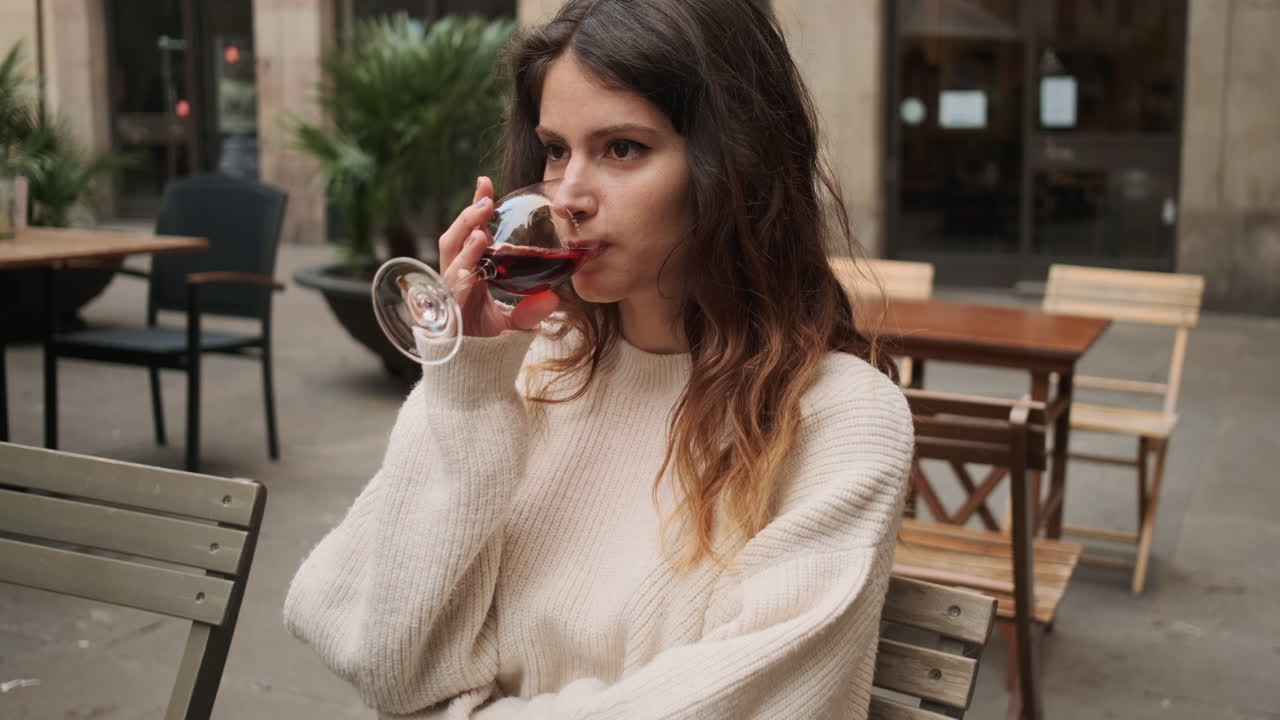 Young girl sitting in a cafe drinking a glass of red wine