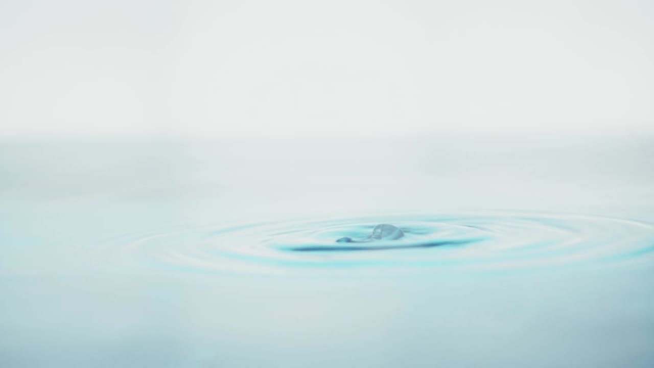 슬로우 모션의 깨끗한 물 표면은 물이 튀는 상점으로 화면을 채우고 기포로 액체 표면을 흔들고 있습니다.