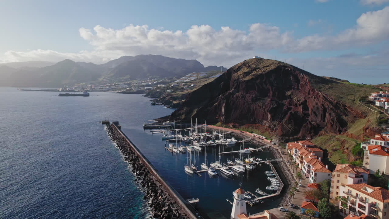 Aerial view of a harbor and marina with mountains in the background