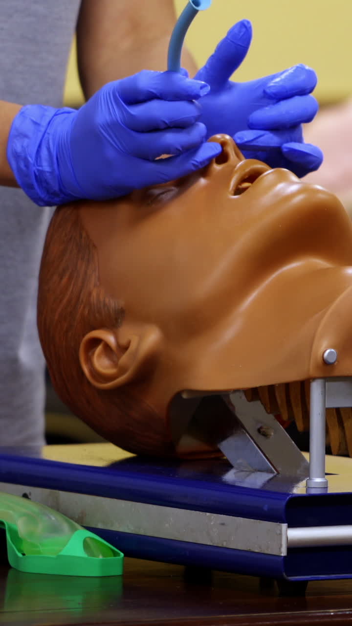 Medic shows how to insert oxygen tube in nose of a medical dummy. Competent doctor with nesessary instruments in hands. Vertical video