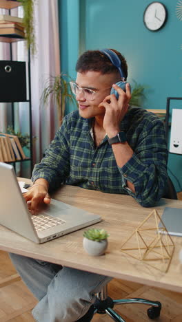 Business-man-listening-music-through-wireless-headphones-relaxing-taking-a-break-laptop-on-table