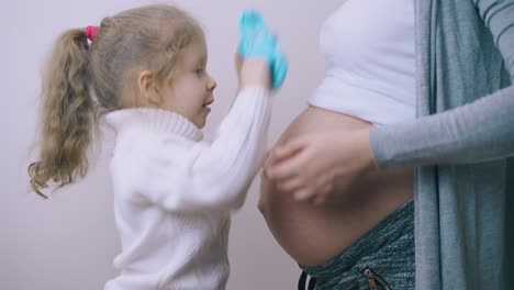 chica hace pasos en mamá embarazada abdomen a mano en botas