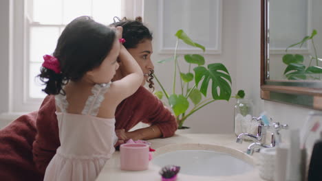 Niña-Feliz-Cepillando-El-Cabello-De-Su-Madre-En-El-Baño-Mamá-Preparando-A-Su-Hija-Por-La-Mañana-Disfrutando-De-La-Paternidad-Cuidando-Al-Niño