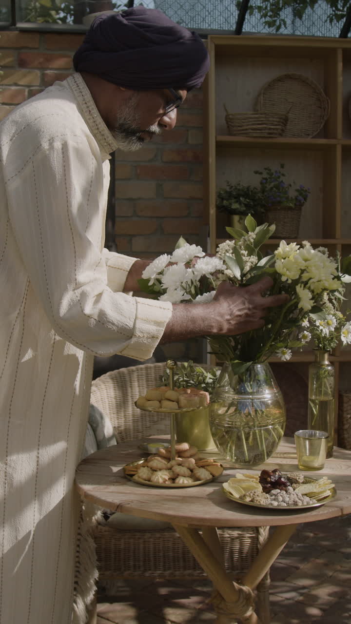 Man Arranging Flowers and Food on an Outdoor Table