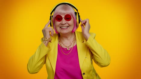 Senior-woman-listening-music-on-headphones-dancing-disco-fooling,-having-fun,-gesticulating-hands