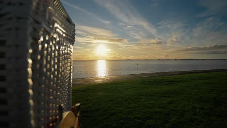 Puesta-De-Sol-Dorada-Sobre-El-Mar-Del-Norte,-Revelando-La-Silla-De-Cesta-De-Playa-Strandkorb---Parte-Trasera-Del-Carro