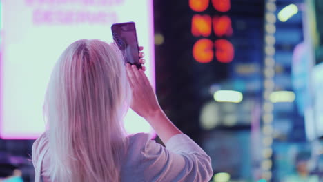 retrato de una mujer atractiva tomando fotografías de lugares de interés en times square se encuentra en el fondo