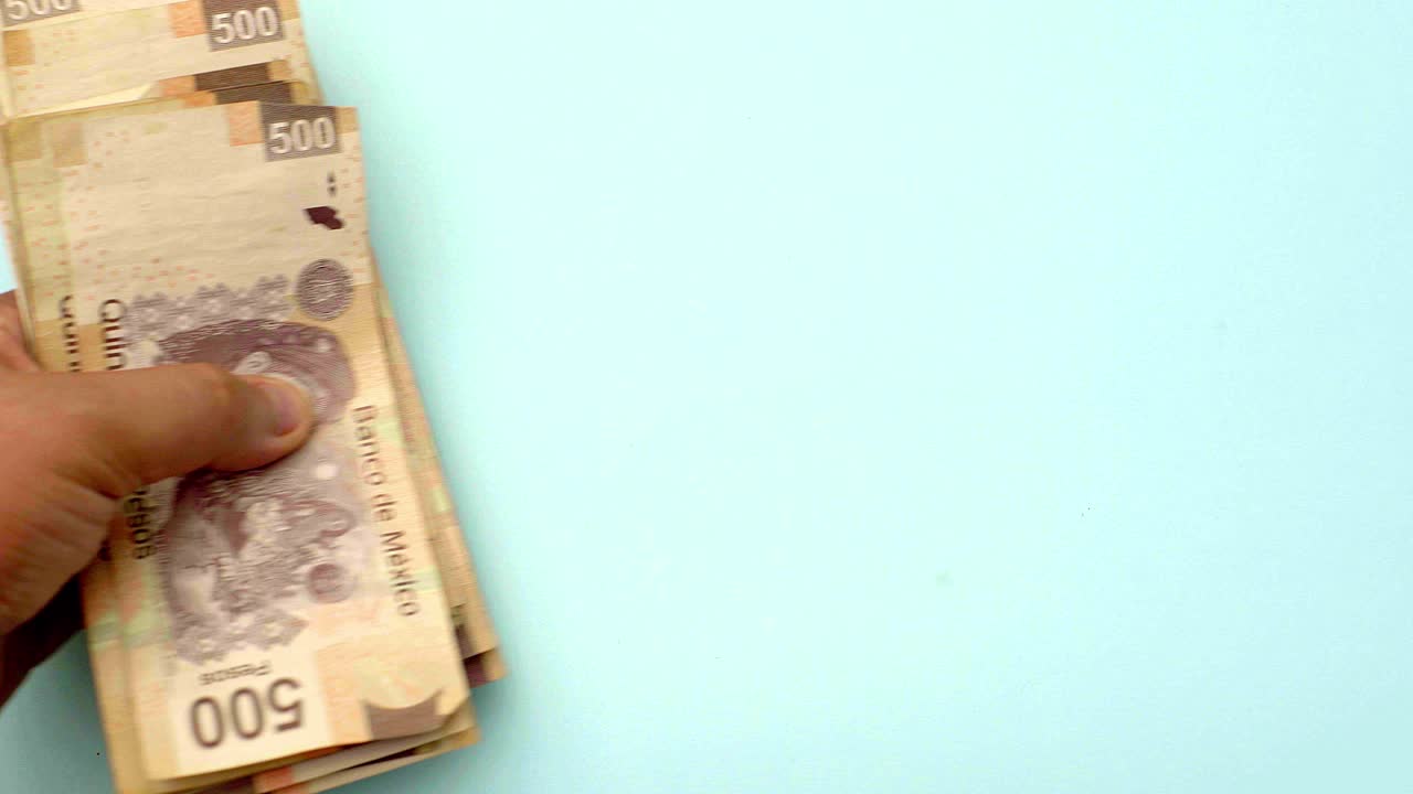 entregando billetes mexicanos de quinientos dólares, transfiriendo el concepto de dinero con escritorio turquesa - top shot