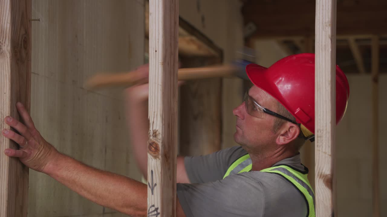 Construction worker nailing wall studs