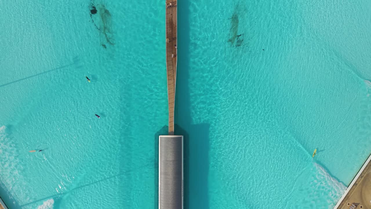 Prospettiva aerea dei surfisti all'SRF PARK TLV, che mette in risalto l'esclusiva piscina a forma di ventaglio e l'acqua cristallina