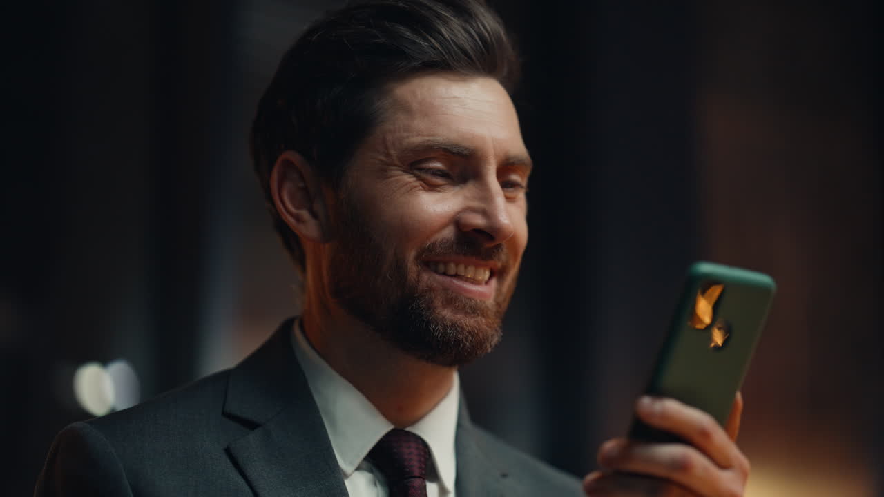 Night manager holding smartphone relaxing at dark room closeup. Smiling director