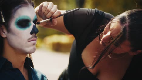 makeup artist applying day of the dead face paint