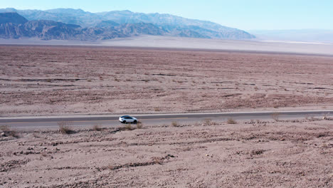 Luftaufnahme-Eines-Autos,-Das-Auf-Einer-Autobahn-Durch-Eine-Wunderschöne-Wüstenlandschaft-Im-Death-Valley,-Kalifornien,-Uns-Fährt