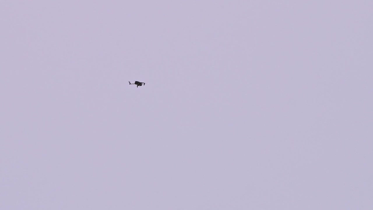 Patruljerende drone, der flyver gennem en åben himmel og skaber en minimalistisk komposition med negativt rum