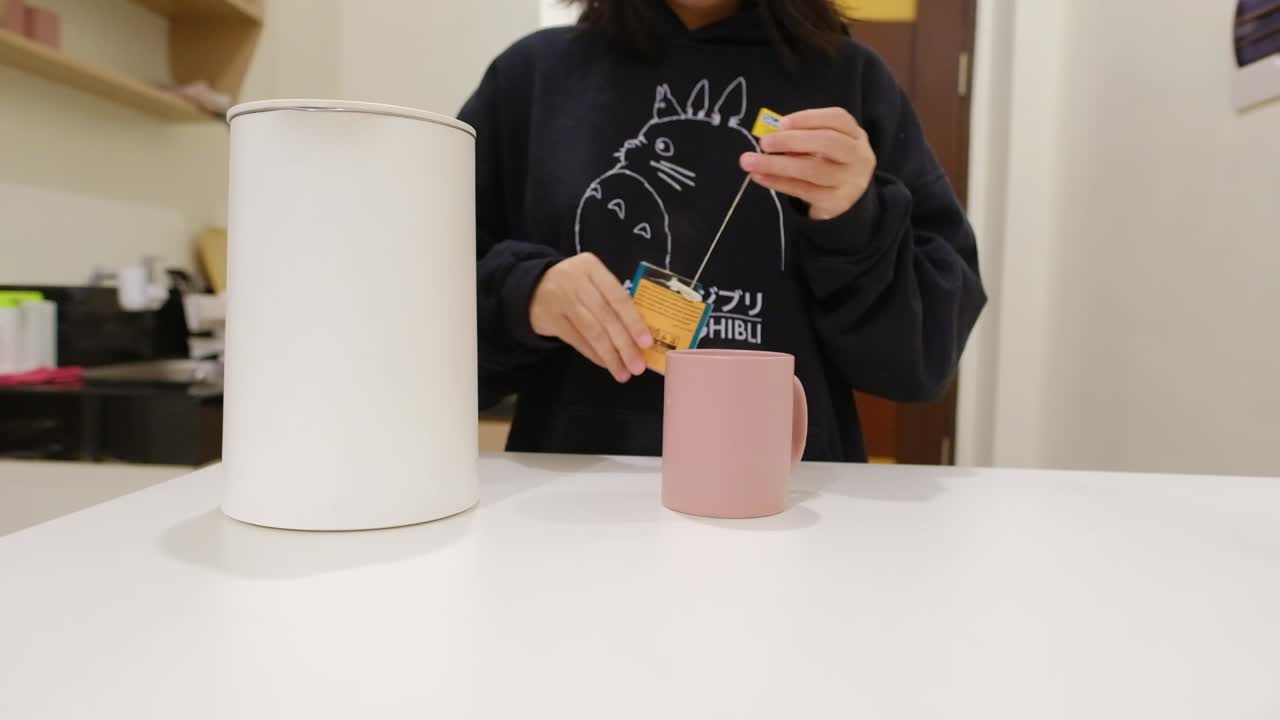 hermosa joven asiática haciendo una taza de té en una cocina brillante