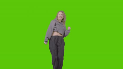 full length studio shot of young woman having fun dancing against green screen 2