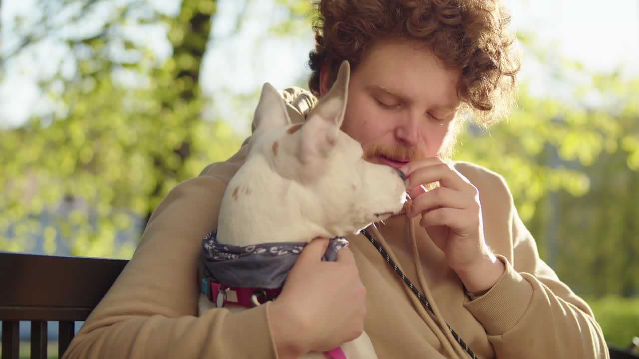 A man and his dog share affectionate moments in a park