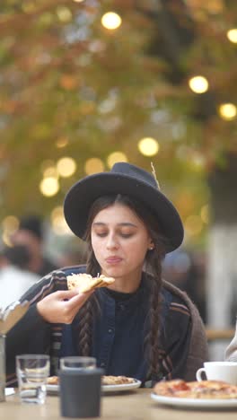 young woman eating pizza outdoors