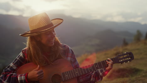 un chitarrista felice che sorride all'aperto in montagna. una ragazza gioiosa che suona la chitarra.