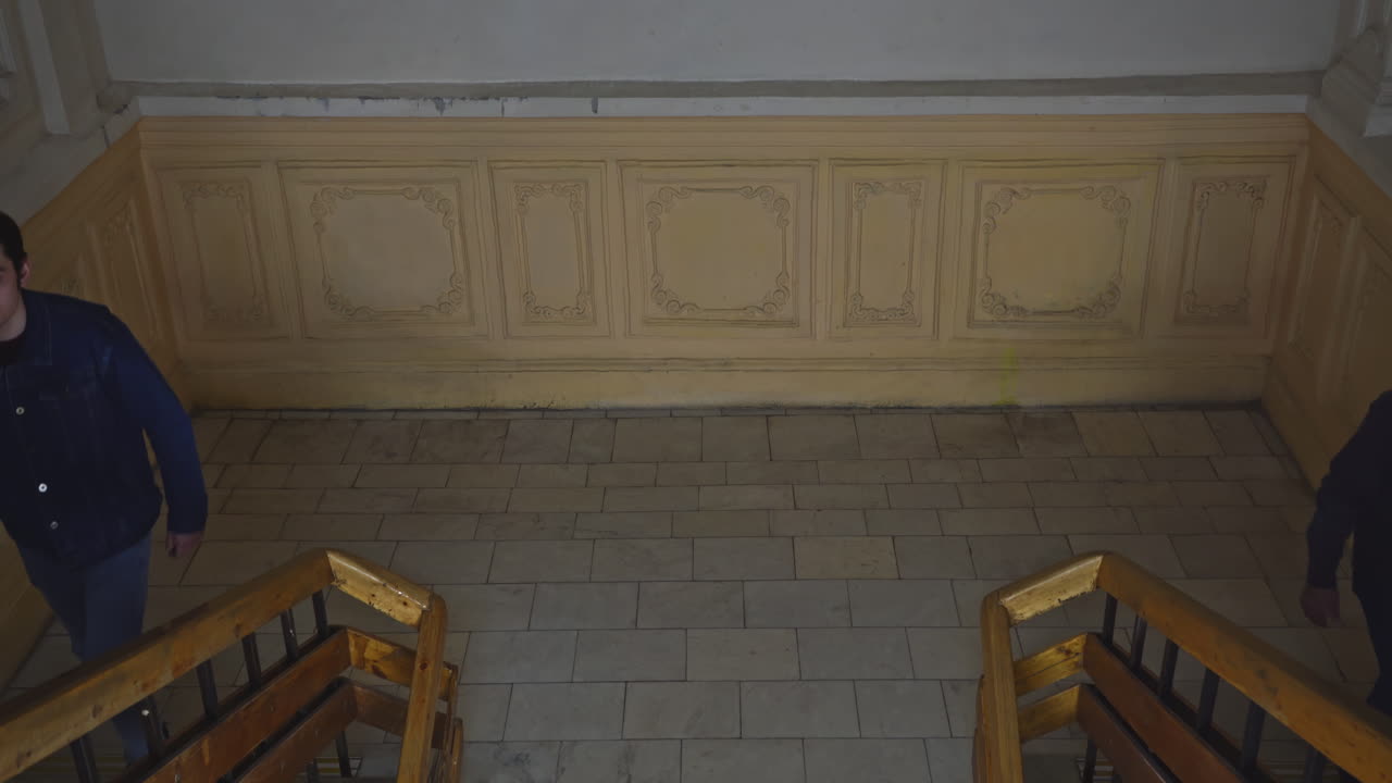 두 남자가 오래된 건물의 계단을 올라가고 있다.