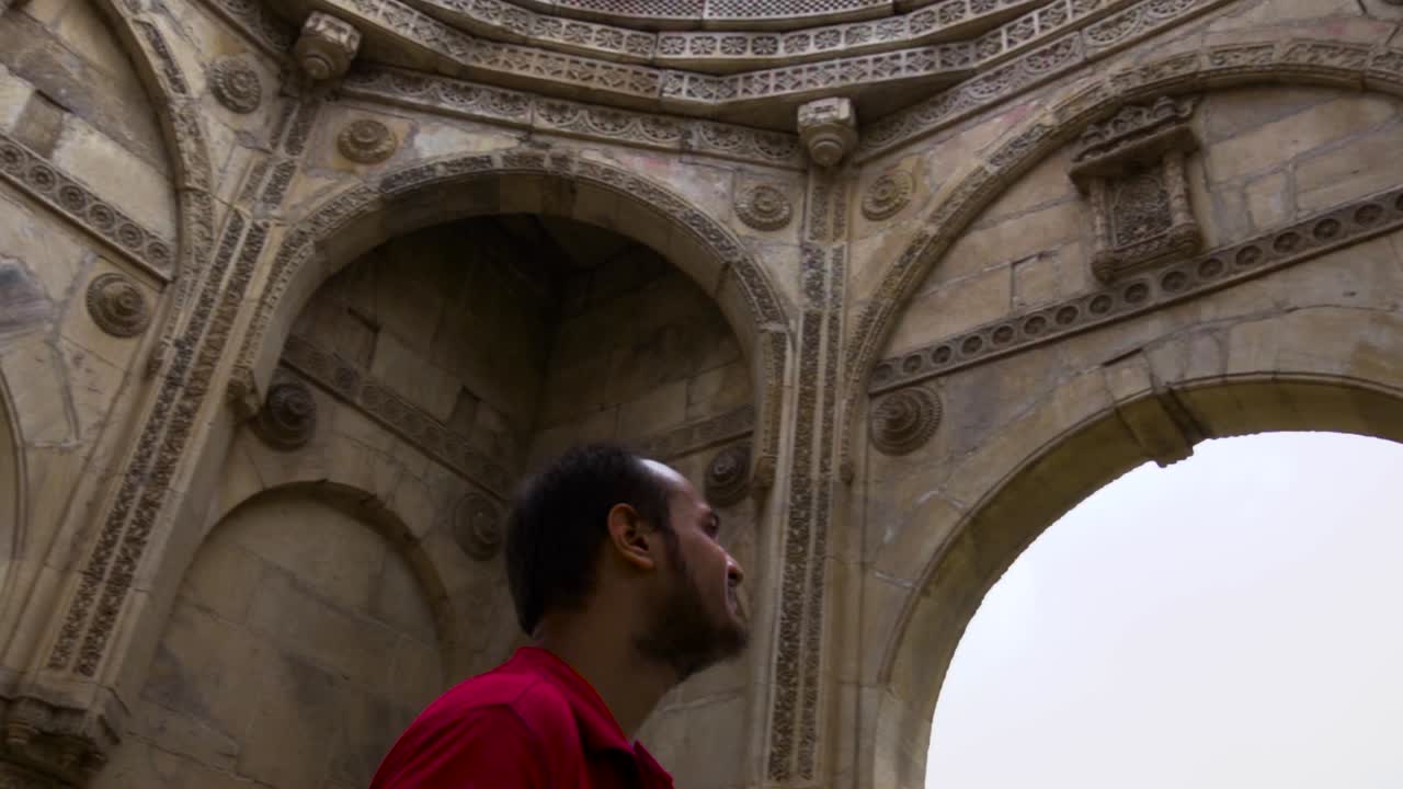 Exploration de l'architecture ancienne : Un homme contemple avec admiration des arches en pierre ornées