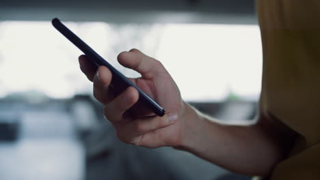 young man typing message on mobile phone skatepark. male hands using smartphone