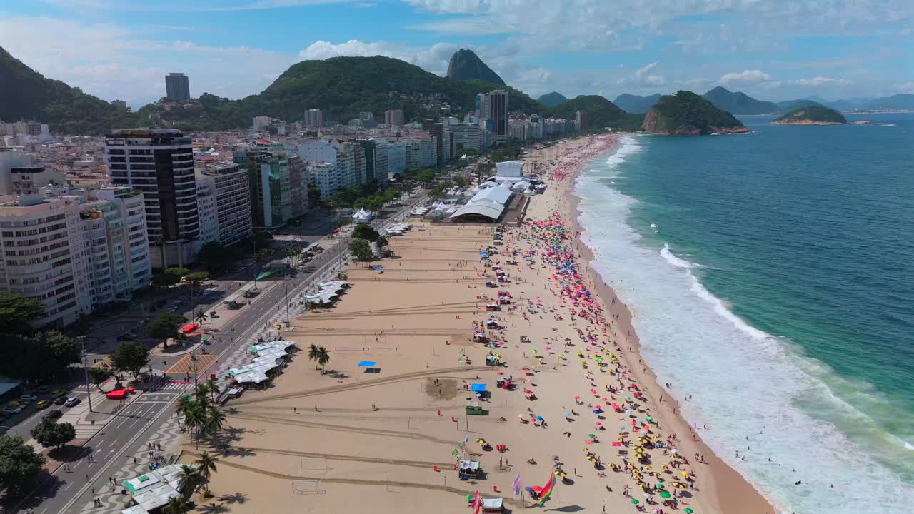 Aerial flyover of sunny Copacabana Beach with Sugarloaf and towering Rio skyscrapers