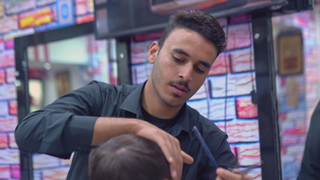 barbero corta el cabello de un hombre con tijeras en una barbería
