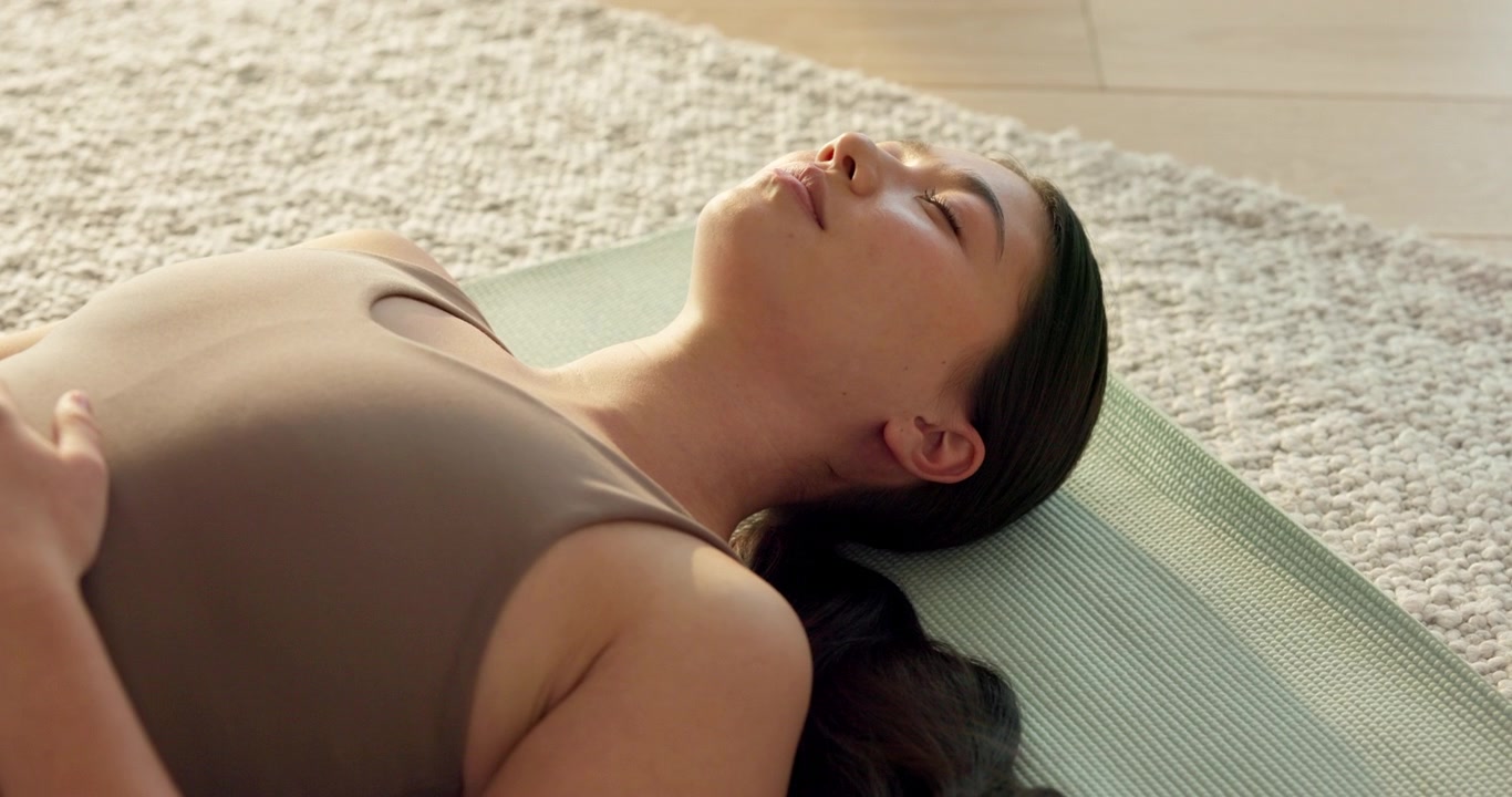 Giovane donna che pratica la posizione yoga Savasana sul tappetino
