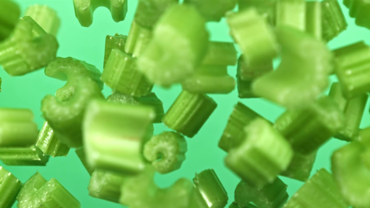 Hakkede selleristykker svævende i super slowmotion på grøn baggrund