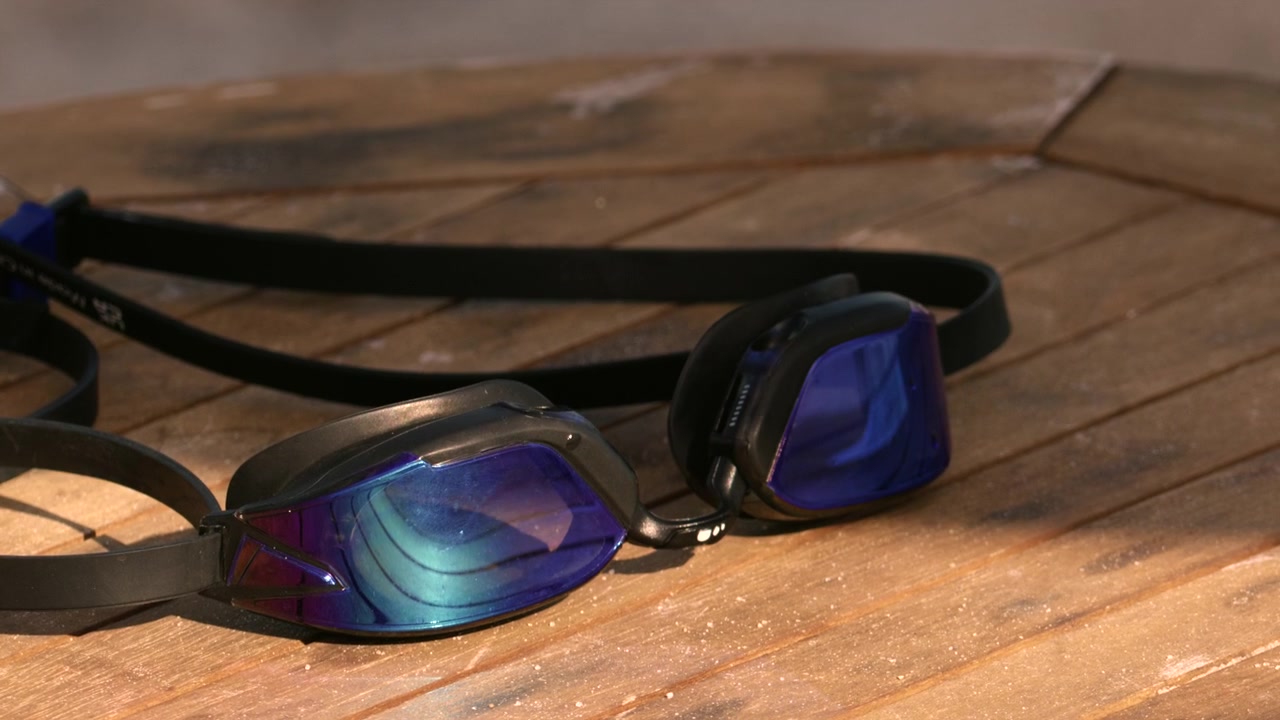 Pair of blue mirrored swimming goggles resting on textured wooden planks after a refreshing swim. Ready for aquatic sports