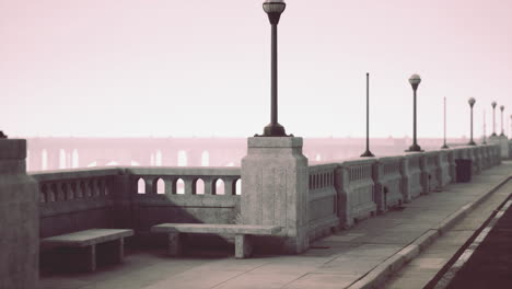 a view of a bridge and sidewalk with street lights on a misty day