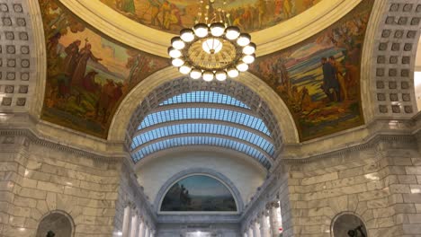 Standing-on-the-floor-of-the-Utah-state-capital-looking-at-the-hand-painted-mural-panning-down-to-see-chandelier-beautiful-archways-and-marble-walls