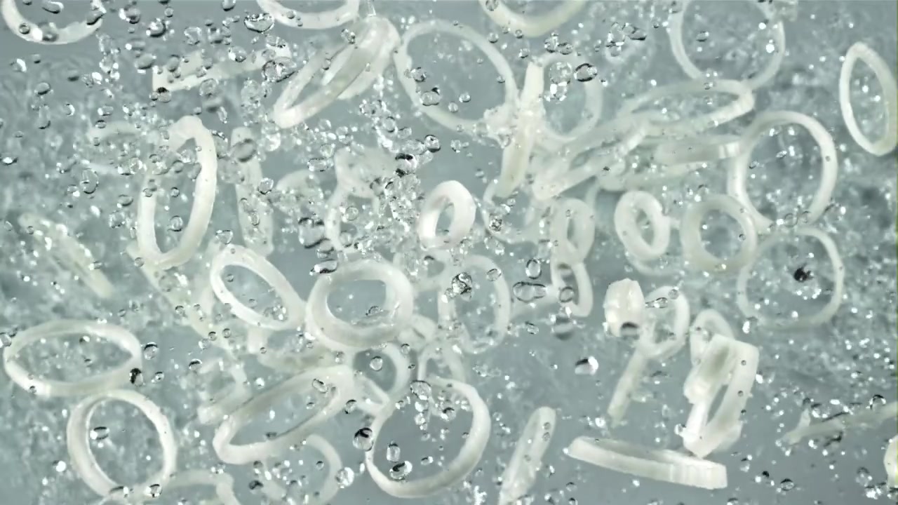 Slowmotion af hvide løgringe, der plasker i vand