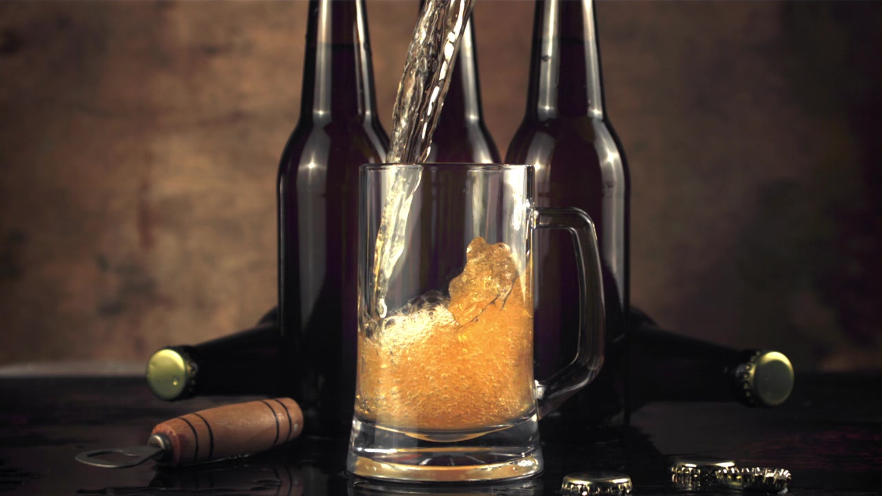 Versamento al rallentatore di birra dorata in un boccale di vetro