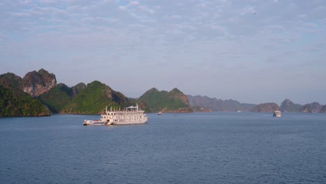 ha long bay vietnam, cruise ships touring through limestone mountains and islands at sunrise