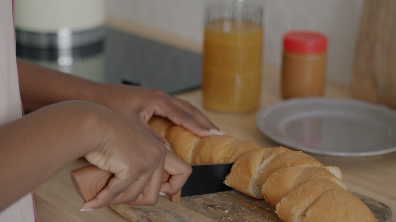Woman cutting a baguette in a kitchen