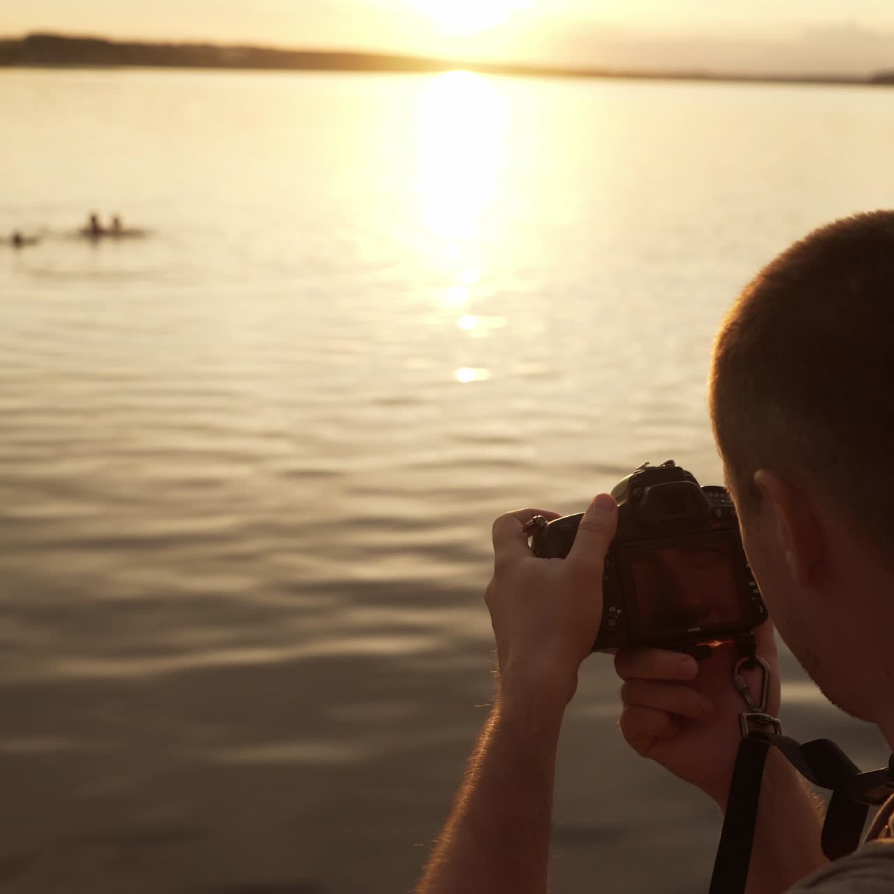 Tourist is photographed on the beach of people swimming in the river at sunset