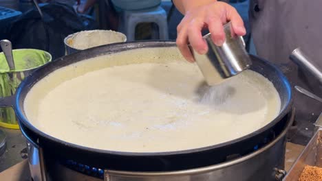 a close-up of a vendor making large peanut pancakes, aka apam balik, on a hawker street food stall at a pasar malam in ss2, petaling jaya, malaysia