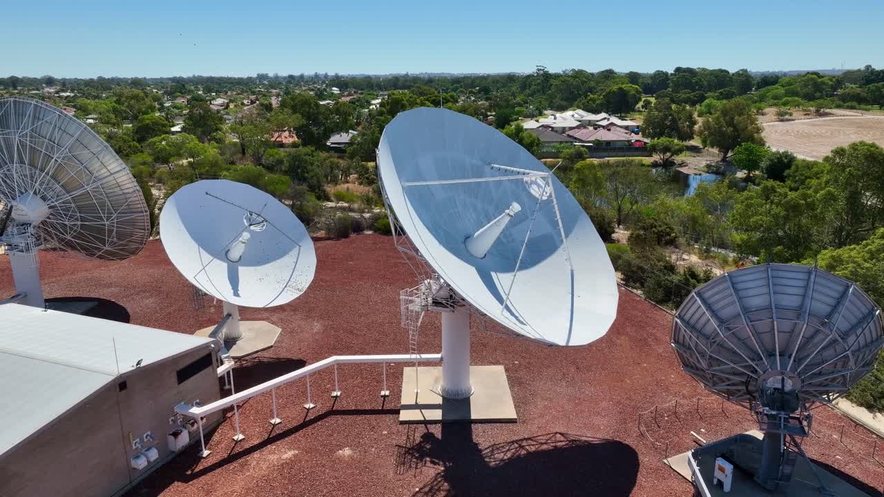 Closeup Of Satellite Dishes In Ground Station Surrounded By Green Trees. orbiting drone shot
